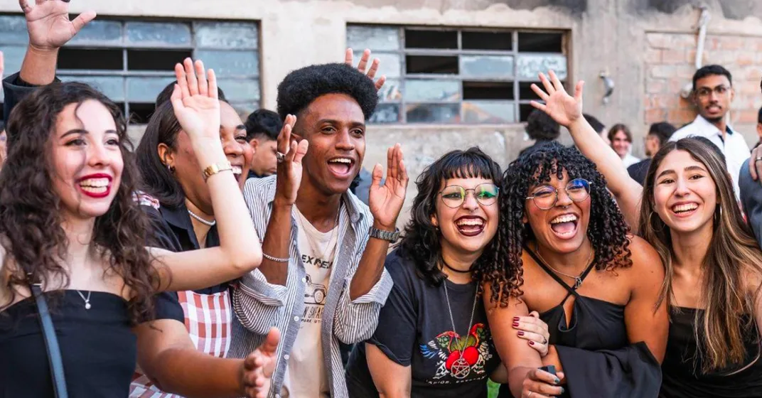 Jovens comemorando juntos com os braços erguidos