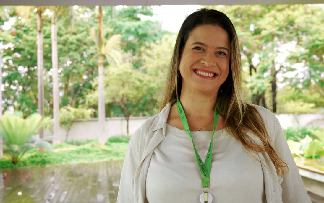 Voluntária sorrindo ao ar livre, com o crachá da companhia