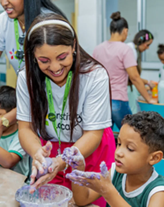 Voluntária e criança brincando com massa em uma oficina
